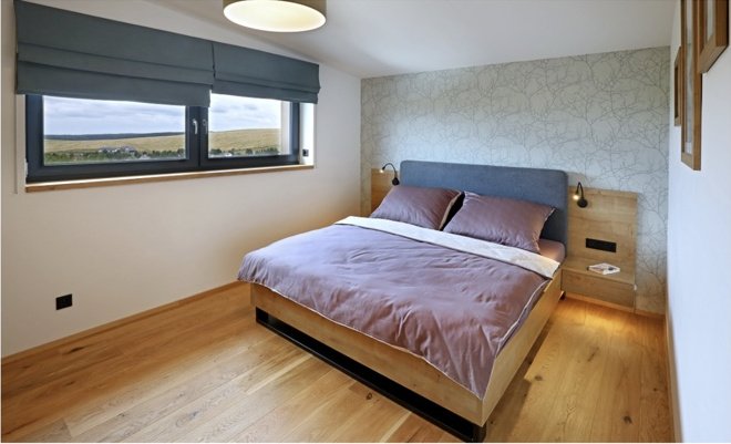 Širší pohled na ložnici s dvoulůžkem a oknem